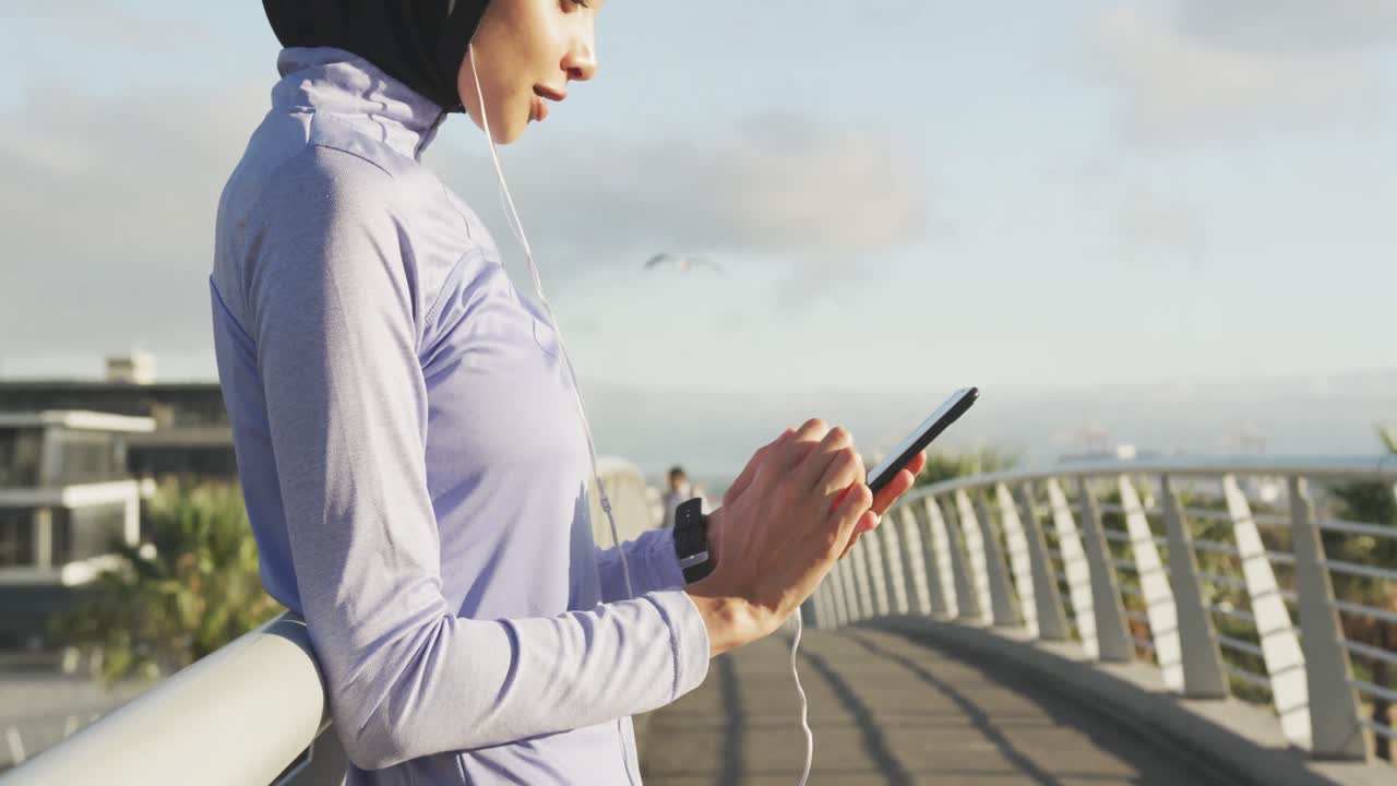 Woman wearing hijab listening music outside
