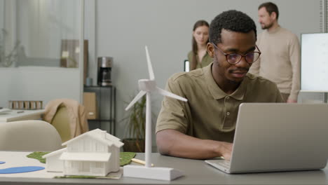 businessman using laptop sitting at table with windmill model in the office 3