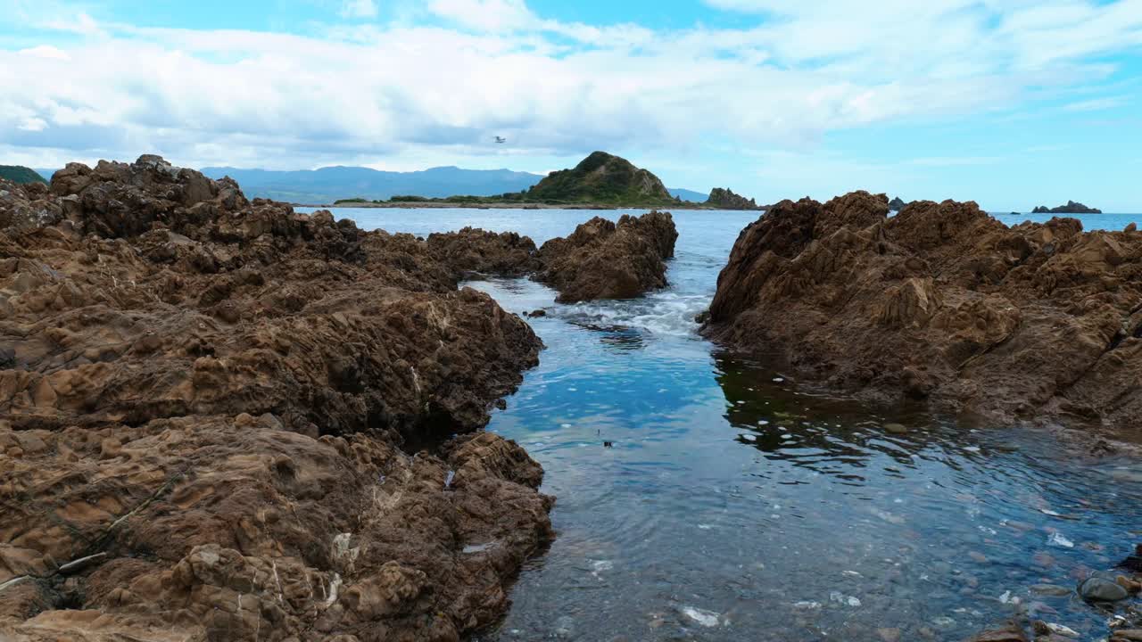 una vista serena de la isla más allá de una tranquila piscina de roca, una pintoresca escena de belleza costera