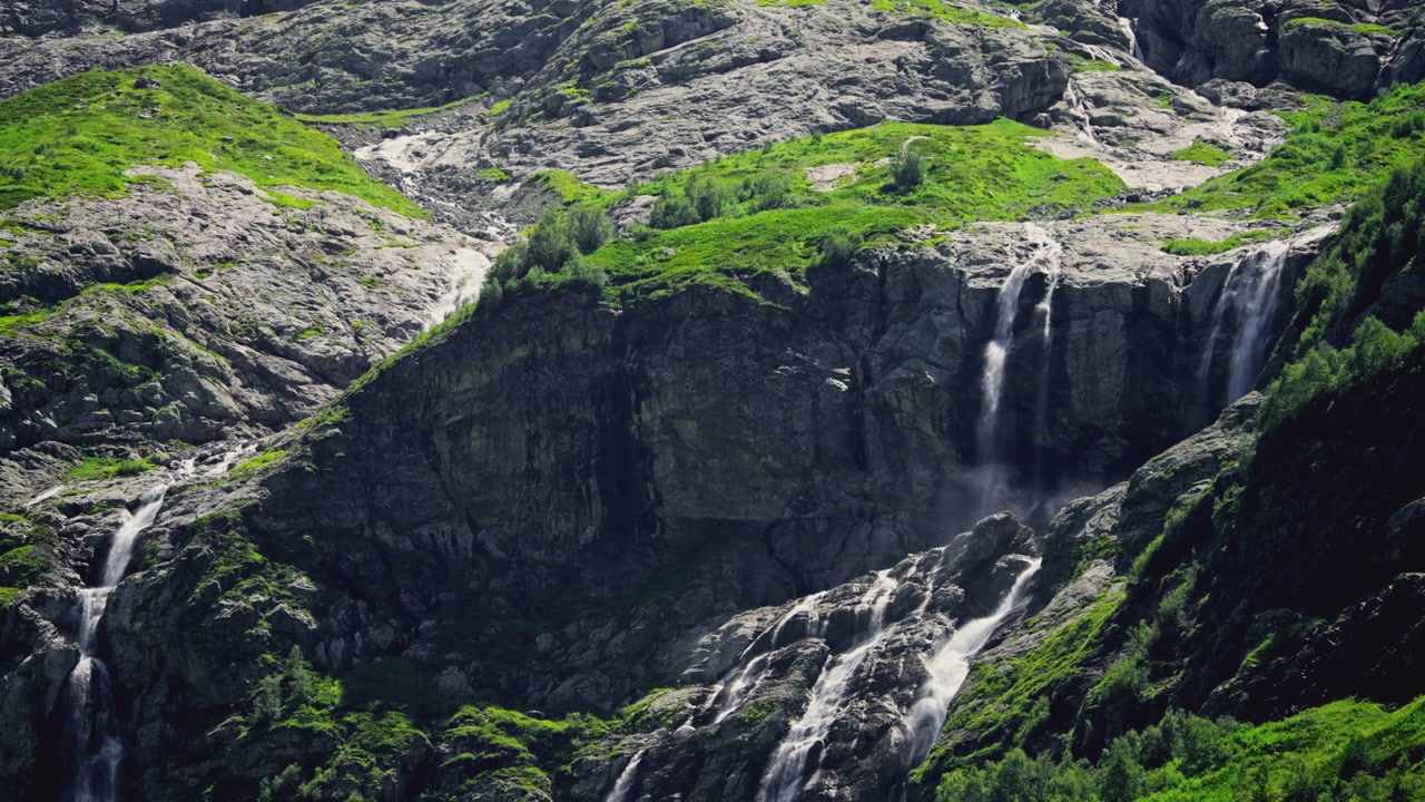Molteplici cascate che scendono da una montagna rocciosa e verde