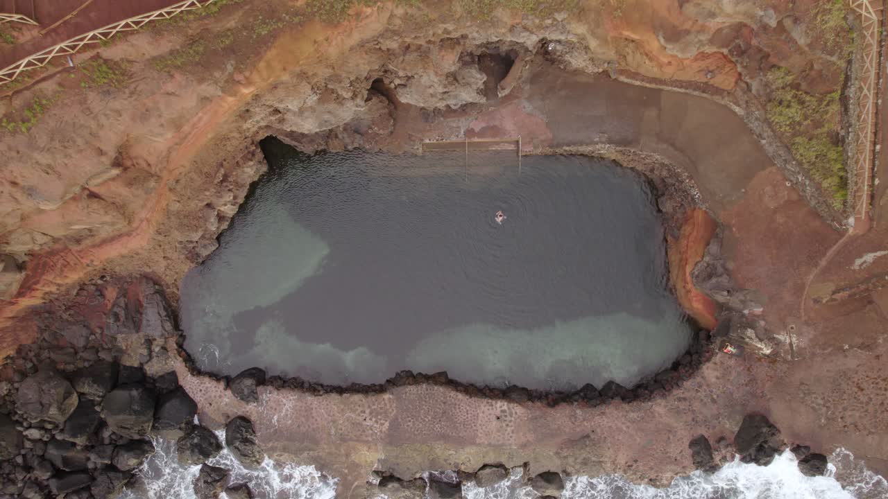 Vista aerea dall'alto di persona che nuota in una piscina naturale a Topo, litorale di São Jorge