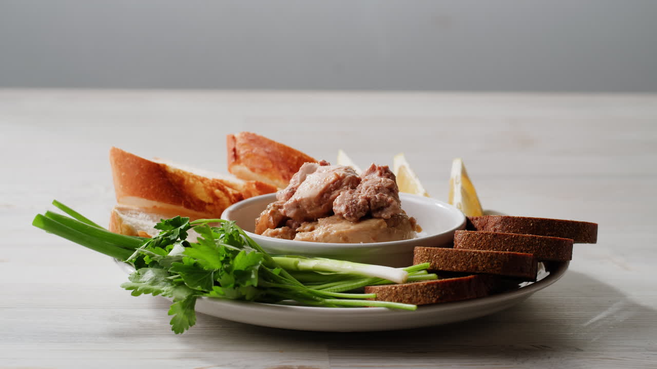 Smoked cod liver in oil in open tin can with fresh greens on wooden table. Seafoods delicacy. High quality 4k footage