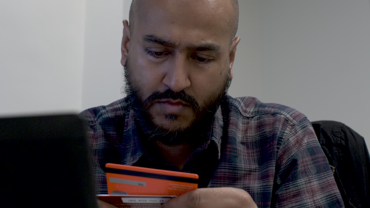 un hombre calvo con una camisa selecciona una tarjeta de crédito de las disponibles