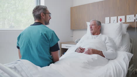 Surgeon-Visiting-And-Talking-With-Senior-Male-Patient-In-Hospital-Bed-In-Geriatric-Unit