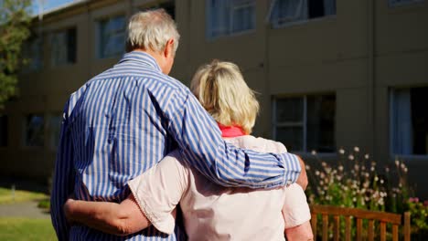 Vista-Trasera-De-Una-Pareja-De-Ancianos-Caucásicos-Activos-Abrazándose-En-El-Jardín-De-Una-Residencia-De-Ancianos-4k