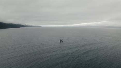 barco de pesca solitario flotando en medio del mar abierto en un día sombrío - disparo de drones