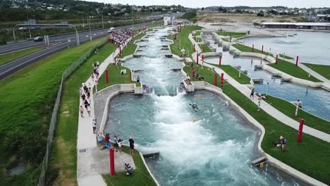 Aerial-wide-shot-in-slow-motion,-capturing-canoe-slalom-in-action-at-Vector-Wero-Whitewater-Park-in-Auckland,-New-Zealand