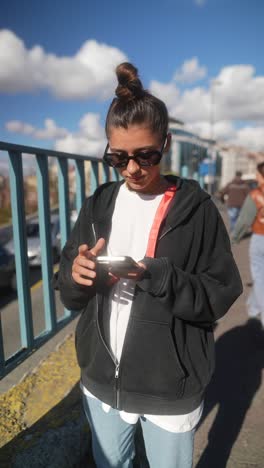 young woman using smartphone on a bridge