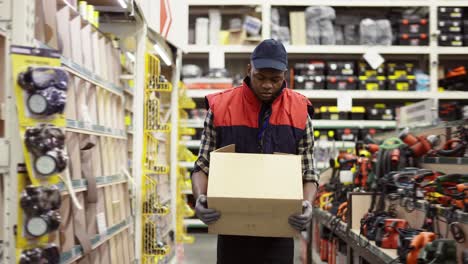 worker in hardware store carrying box