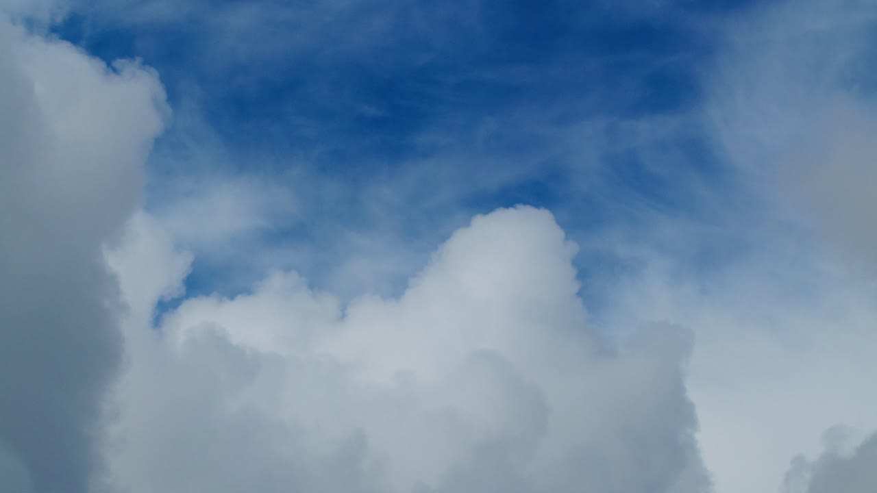 Fluffy clouds float by on a bright day, creating a calm and serene scene