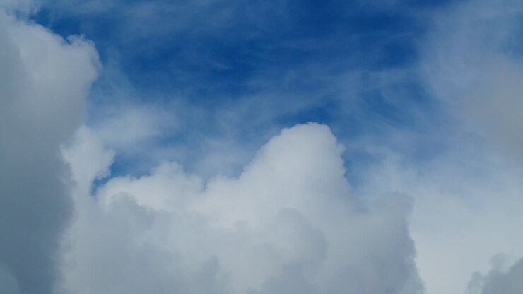 Fluffy clouds float by on a bright day, creating a calm and serene scene