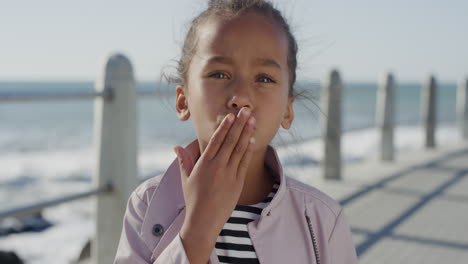portrait-little-mixed-race-girl-blow-kiss-smiling-cheerful-happy-child--enjoying-relaxed-sunny-day-on-beach-seaside