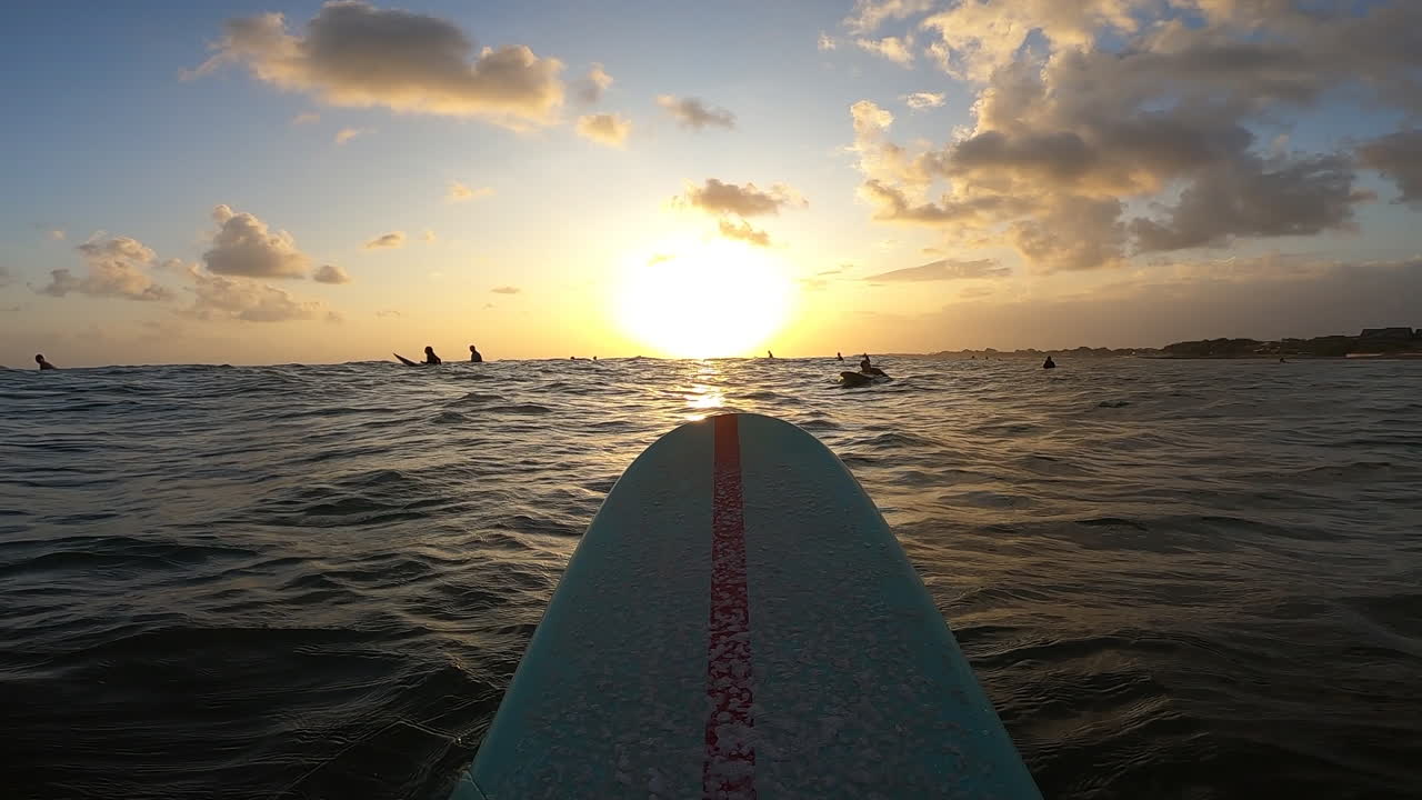 Majestic sunset view from longboard on calm ocean surface, POV