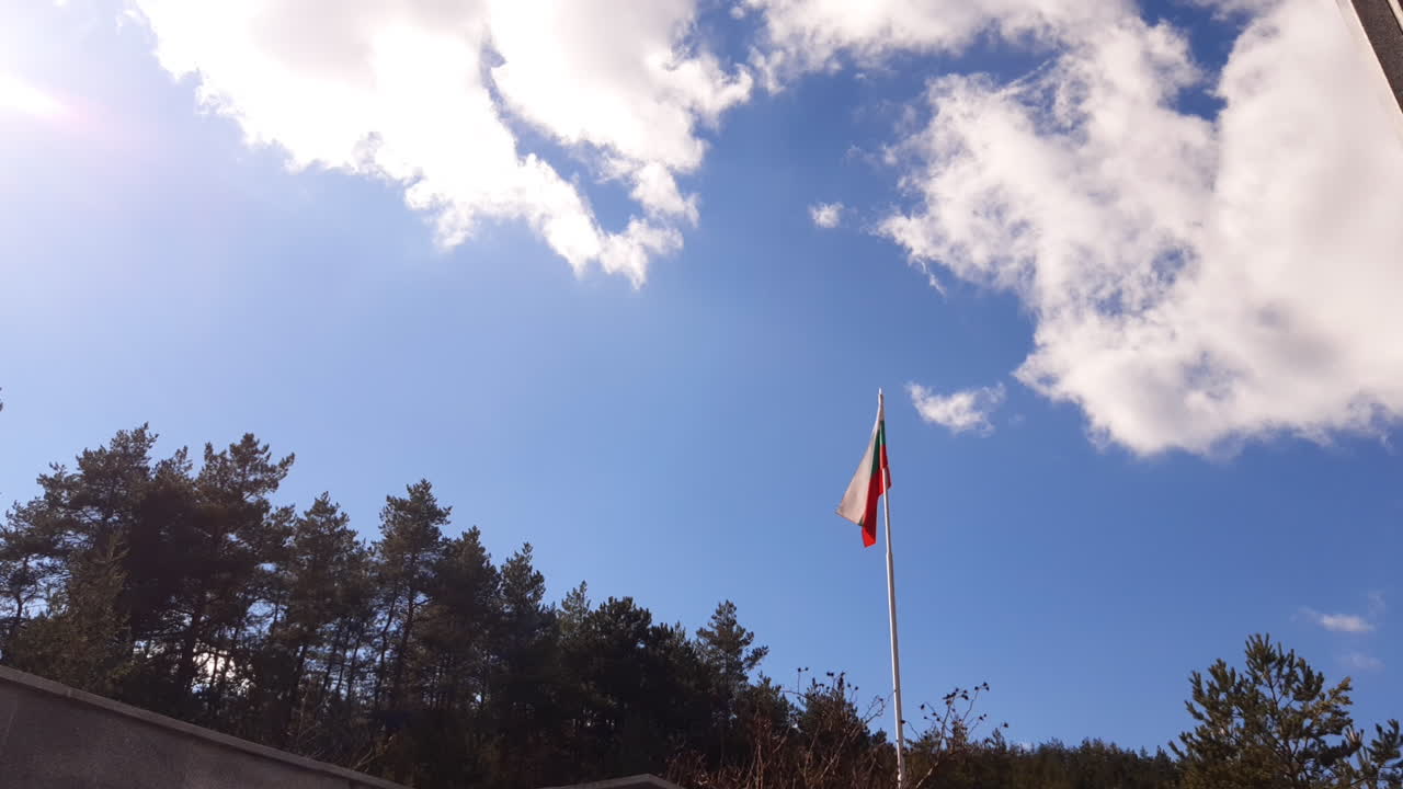 Bendera Bulgaria berkibar di tiang tinggi dikelilingi pepohonan