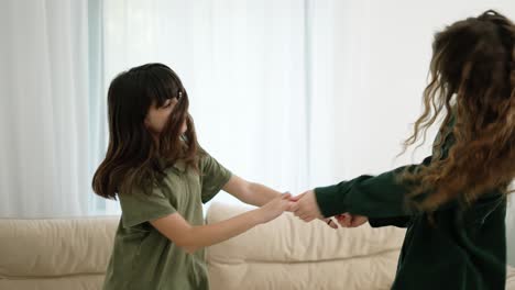 young mother and daughter dancing at home, having fun together, slow motion