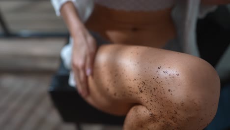 mujer aplicando exfoliante de café a sus piernas