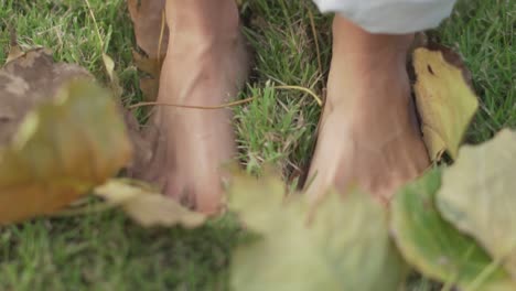 Female-feet-standing-on-green-grass-and-foliage