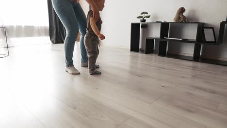 imágenes recortadas de un niño pequeño caminando por la casa entre madre y padre