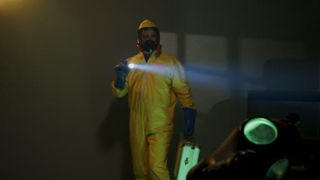 hazmat suit wearing man explores a dark room