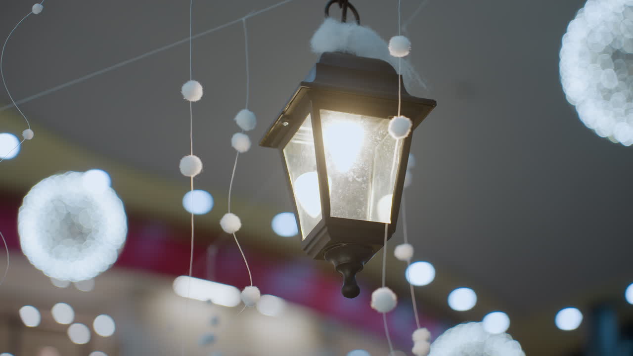 Elegant decorative lantern glowing warmly in a beautifully adorned mall, surrounded by festive white hanging ornaments and blurred holiday lights
