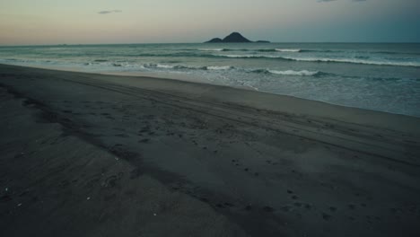 Tilt-up-reval-view-from-a-beach-of-Moutohora-island-on-the-horizon-during-the-sunset