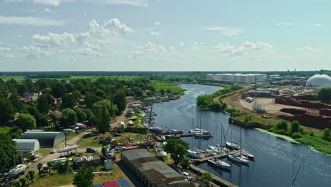 aerial panoramic factory river canal village, buoyant boats, greenery sunny day