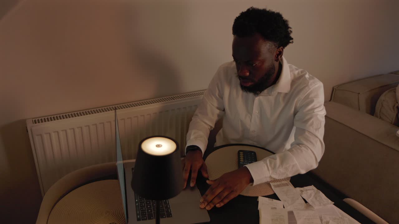 Panning Shot Of Black Male Sorting Out Finances In Living Room in Home