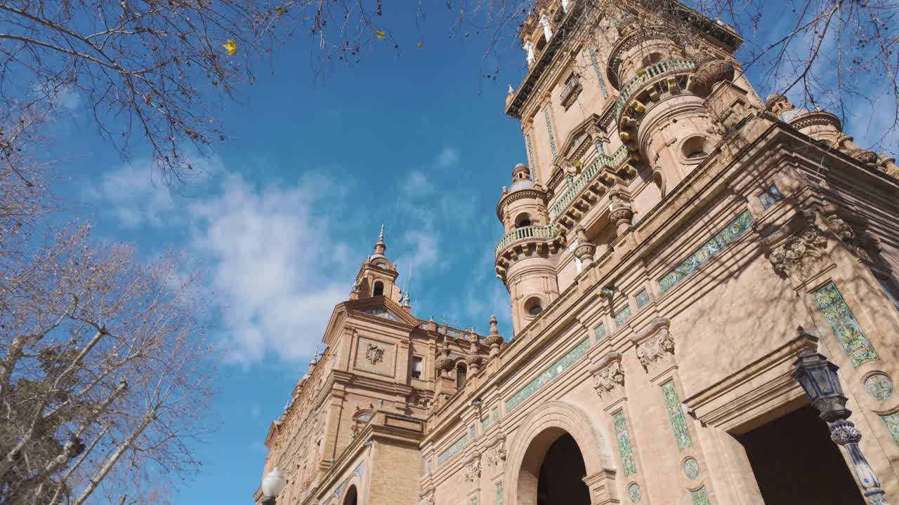 Vista de baixo da torre ornamentada da Plaza de España contra um céu azul em Sevilha, Espanha.