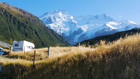 rv in parking lot at base of glacier covered mountains