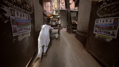 indian man pushing cart down alleyway