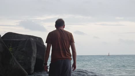 hombre caminando hacia la orilla rocosa con rocas en la playa en vietnam
