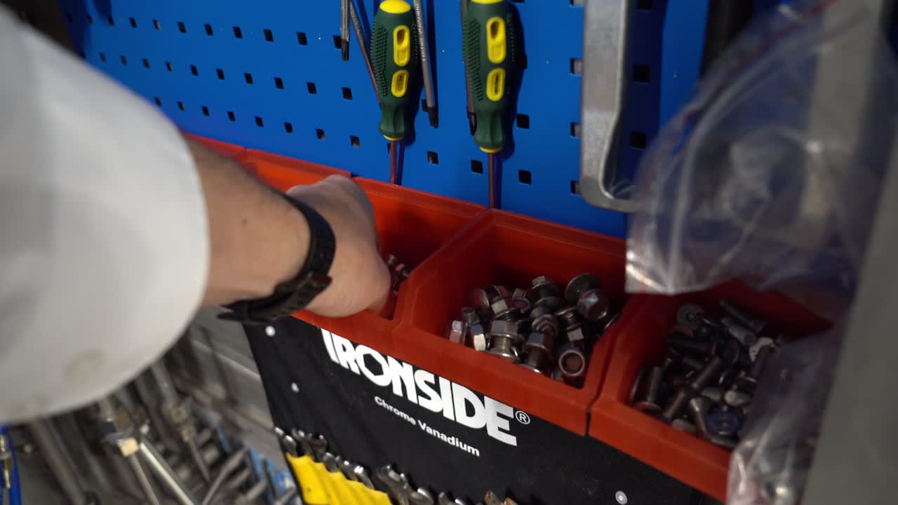 핸드헬드 1인칭 시점에서 빨간색 도구 상자 트레이에서 볼트와 너트를 손으로 집어들기