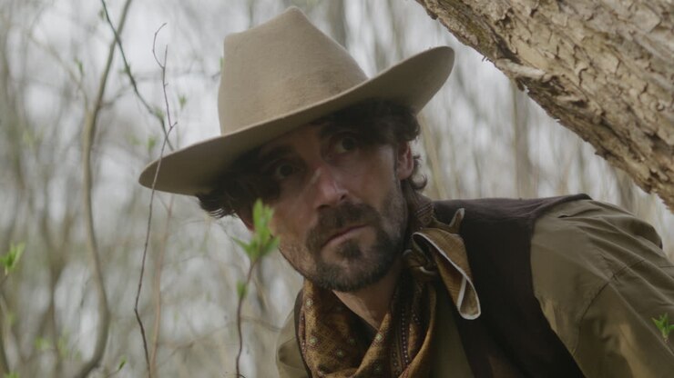 Close up of a wounded cowboy finding his way through wasteland