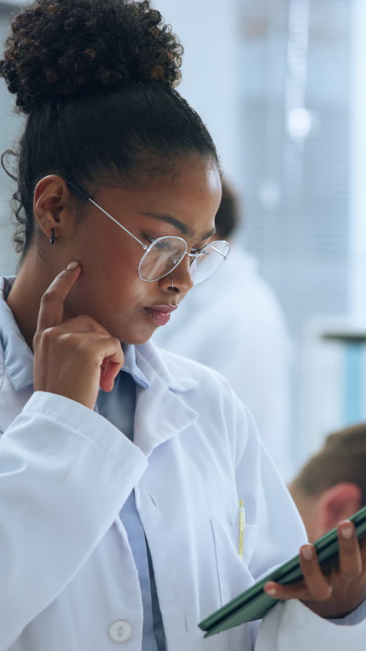 Giovane donna concentrata in camice da laboratorio che usa un tablet in un laboratorio
