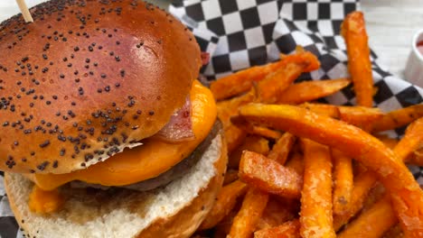 Leckerer-Cheeseburger-Mit-Speck,-Brioche-Brötchen-Und-Süßkartoffel-Pommes,-Ungesundes,-Schweres-Amerikanisches-Essen,-4K-Aufnahme