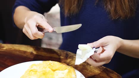 woman buttering bread at a wooden table