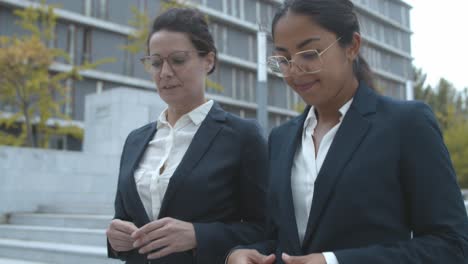 two happy business women talking together while walking near office building