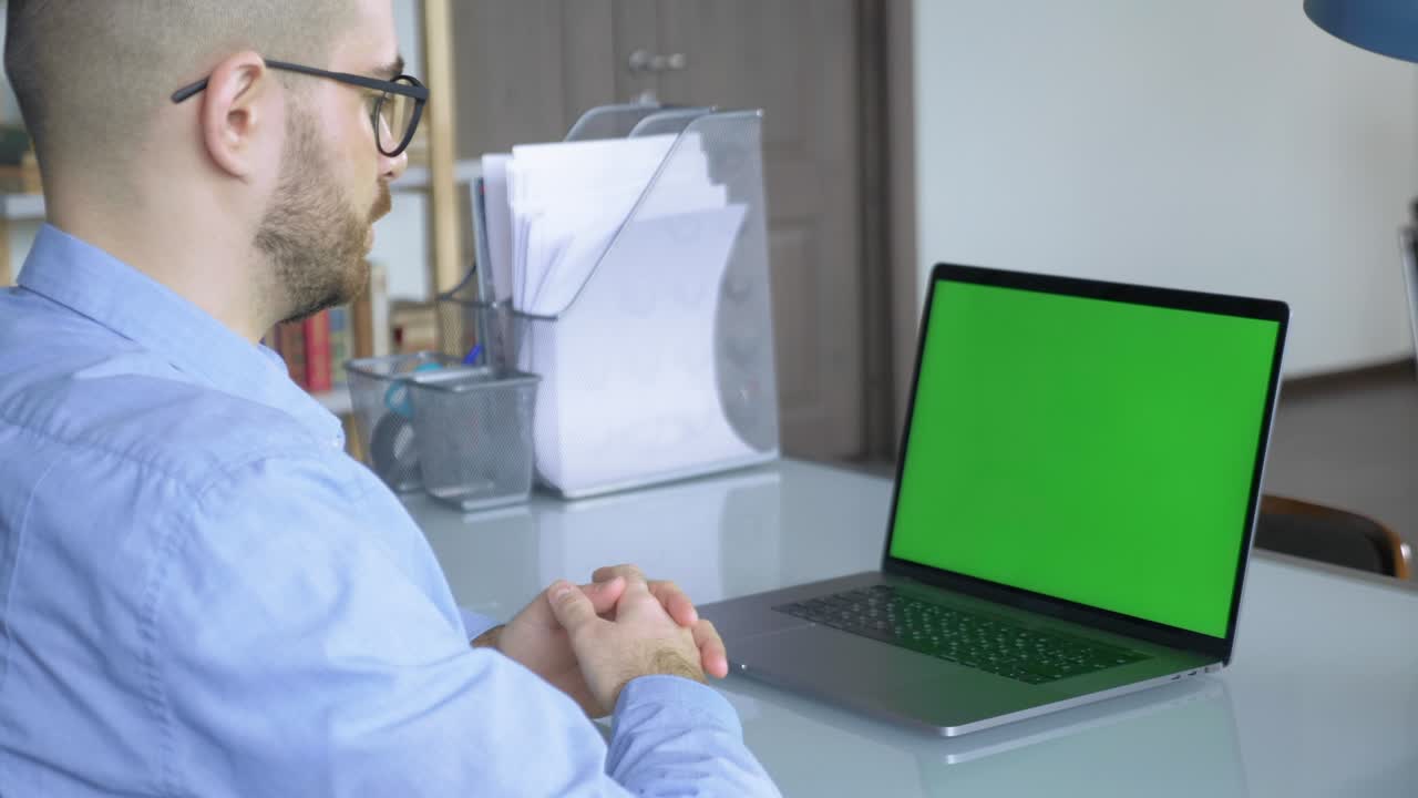retrato en primer plano de dos hombres de negocios caucásicos exitosos usando una computadora portátil con pantalla de tecla de croma verde en la oficina en interiores