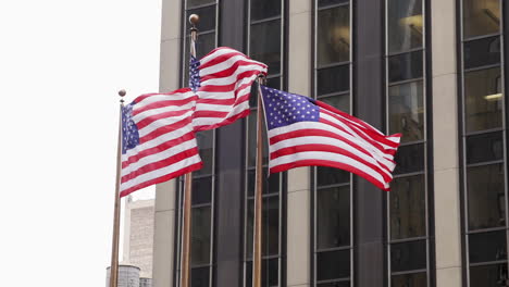 three american flags waving in the wind with new york city building in the background