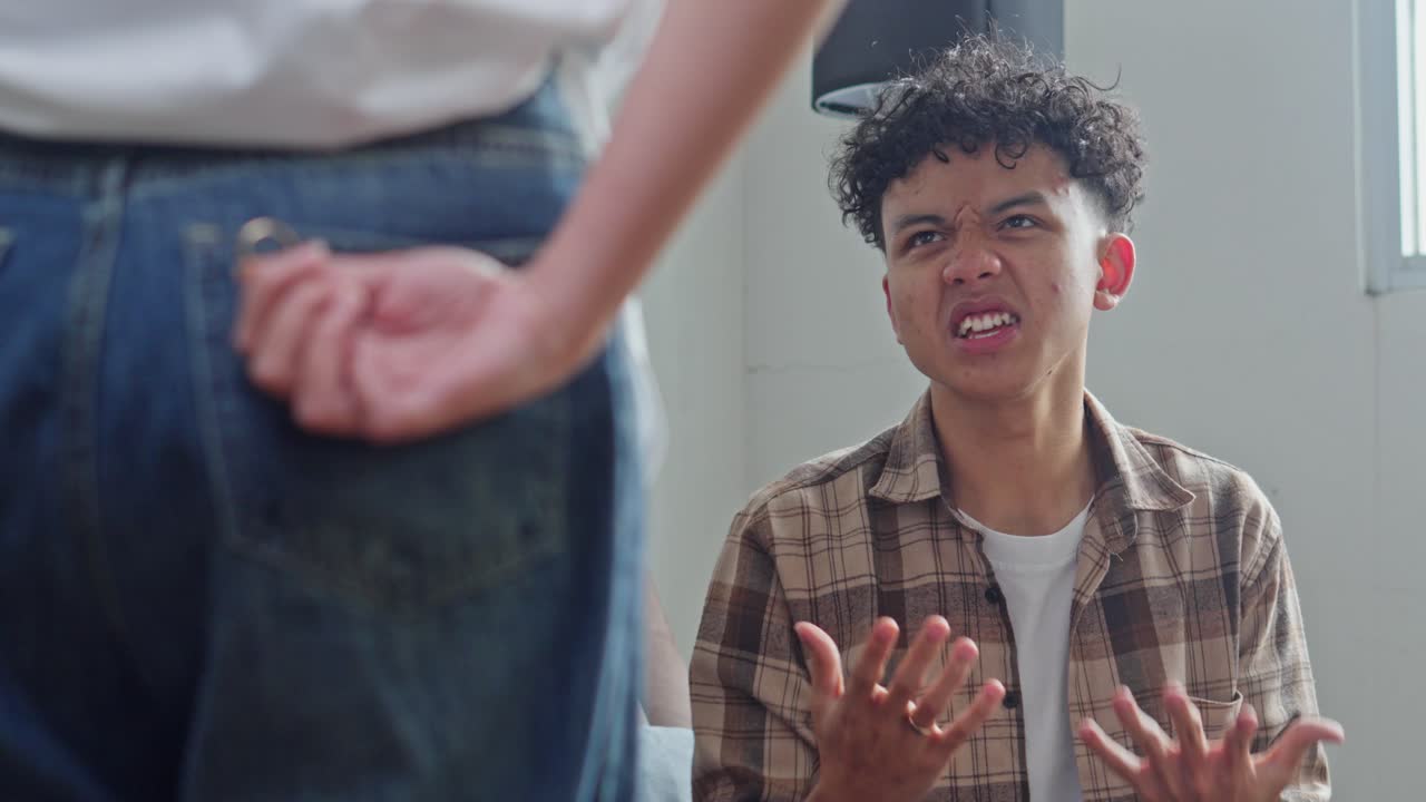 Angry young husband shouting and pointing to wife hides wedding ring trouser pocket