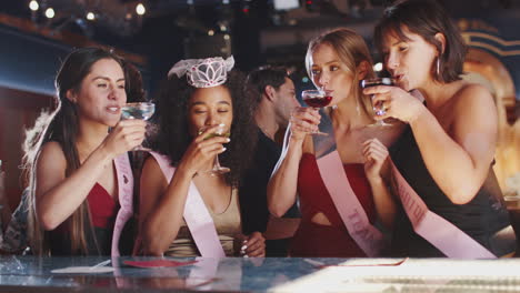 group of female friends celebrating with bride on hen party in bar