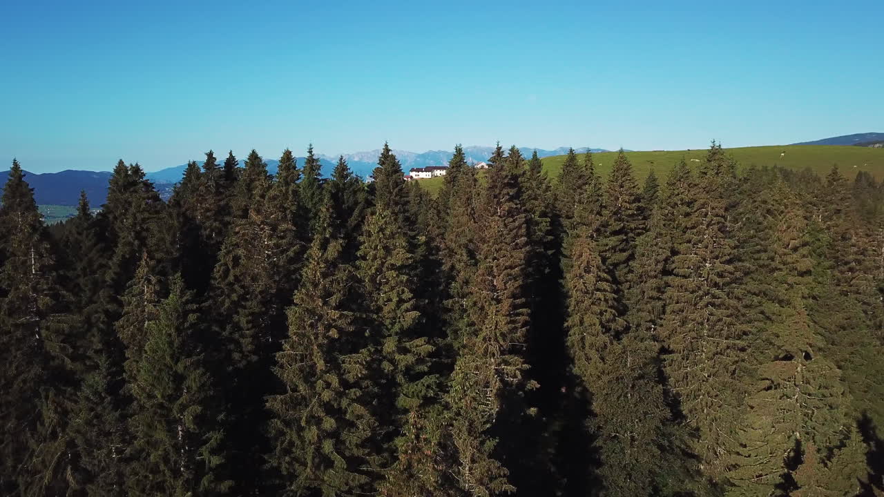 배경에 산봉우리가 있는 언덕 꼭대기에 있는 시골 농장의 모습