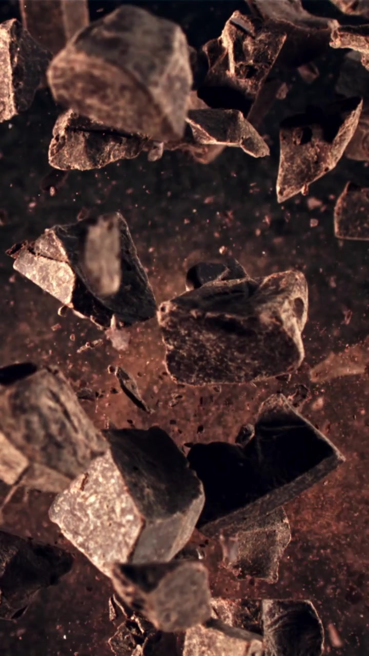 Deliciosos trozos de chocolate y cacao en polvo cayendo en cámara lenta