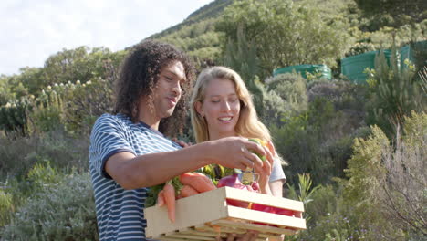 happy diverse couple holding basket of fresh vegetables in garden, slow motion