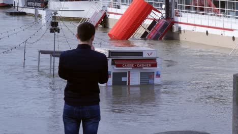 man photographing flooded seine on phone