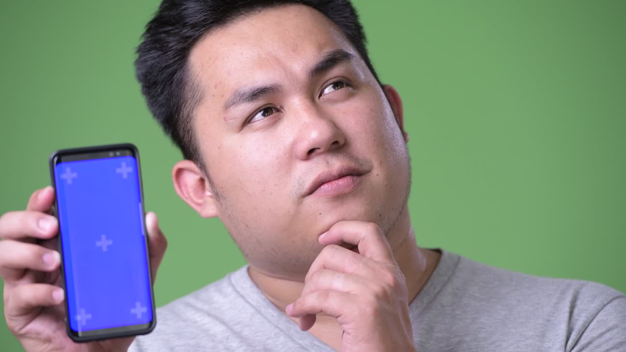 초록색 배경에 젊은 잘생긴 과체중 아시아인