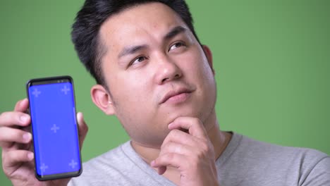 緑色の背景に若いハンサムで太ったアジア人男性