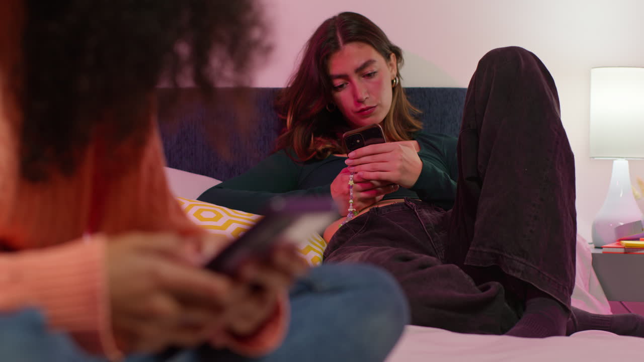 две женщины отдыхают в спальне, пользуются телефонами.