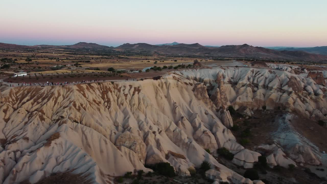 Scogliera e collina che dominano la Valle dell'Amore in Cappadocia, Turchia, con persone e auto in cima