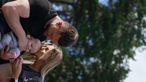 happy caucasian family enjoying free time in nature in summer. loving couple kiss their baby on the head.